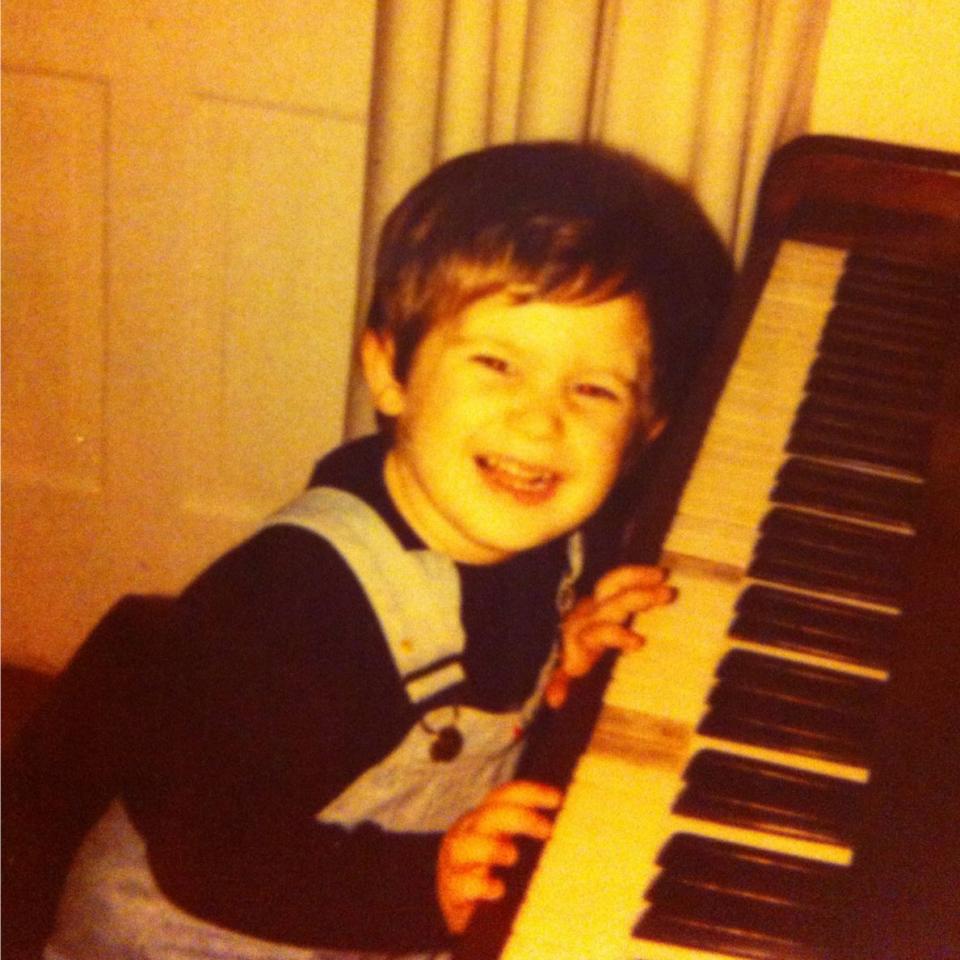 Philipp Eden as a ca. 2 year old child, sitting at the piano, smiling into the camera