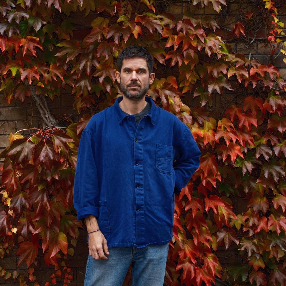 Photography of Philipp Eden at a wall covered with red leaves.