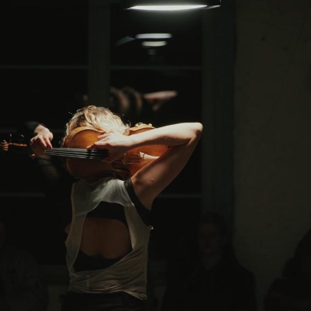 Marie Jeger holding her viola behind her head, playing