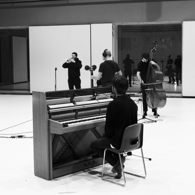 Philipp Eden sitting at the piano, Silvan Schmid playing the trumpet, Xaver Rüegg playing the double bass, Eric LaCasa recording