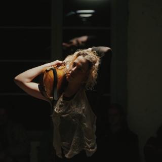 Marie Jeger holding her viola behind her head, playing